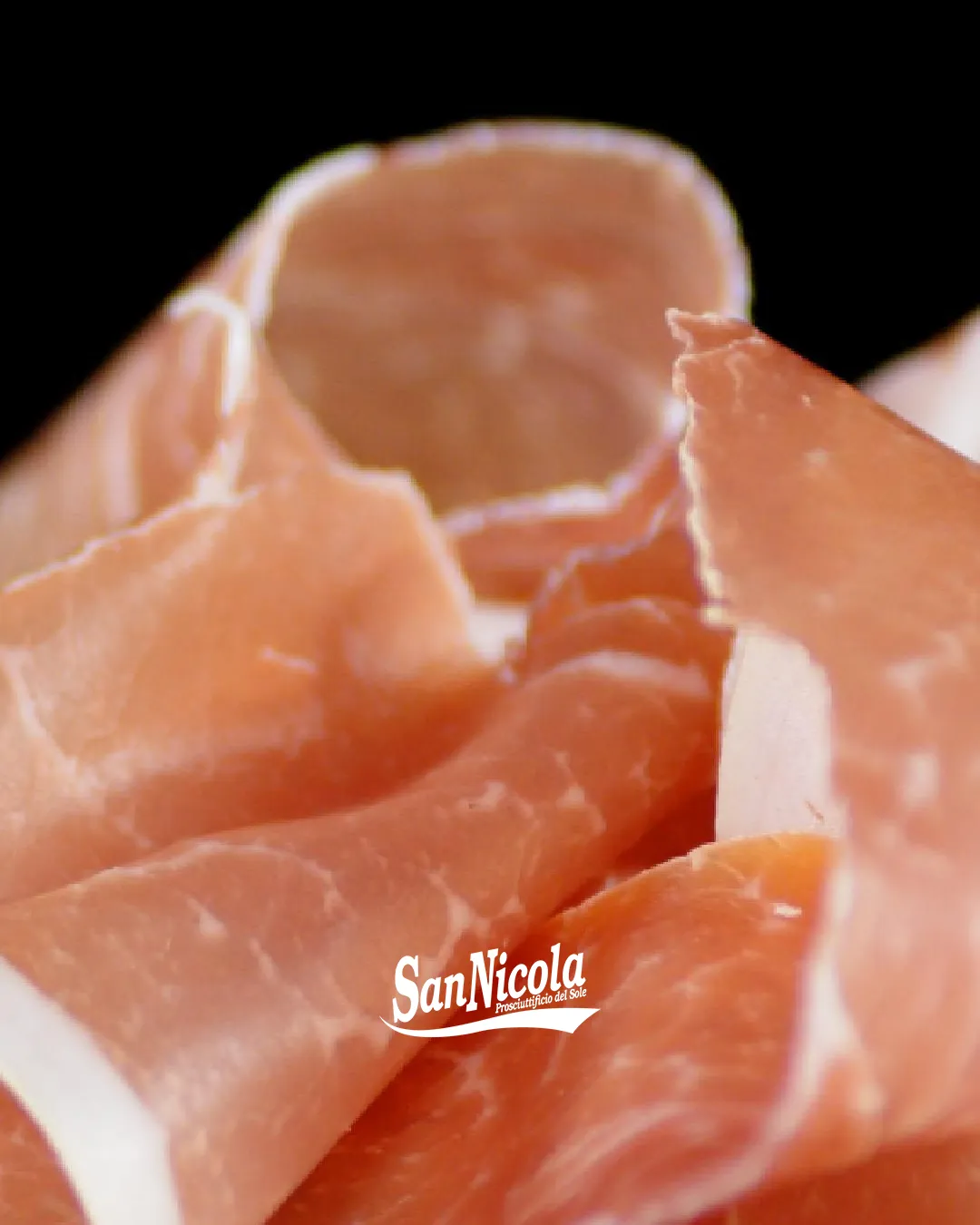 Prosciutto di Parma ravvicinato su sfondo nero.