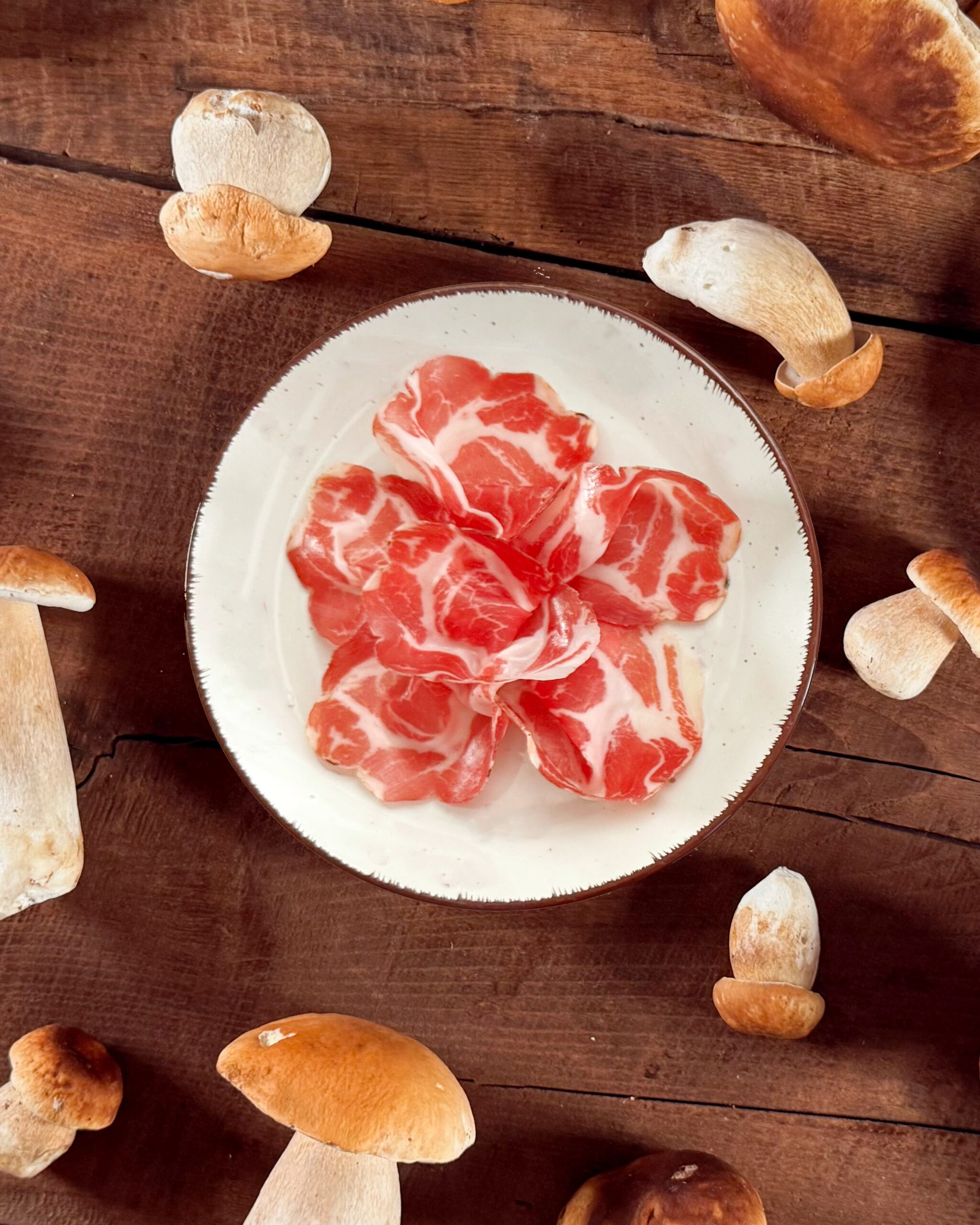Coppa San Nicola DOP circondata da Funghi Porcini.